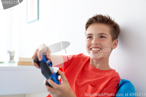 Image of happy boy with gamepad playing video game at home