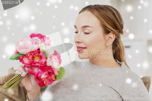 Image of happy woman smelling flowers at home