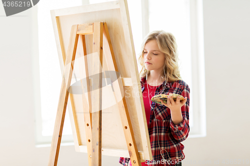 Image of student girl with easel painting at art school