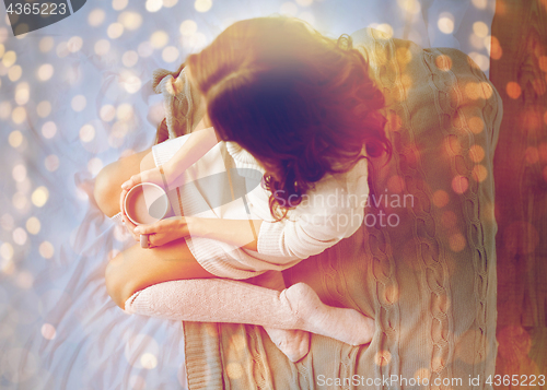 Image of woman with cocoa cup in bed at home