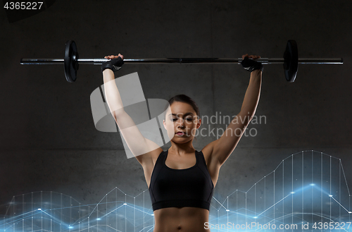 Image of young woman flexing muscles with barbell in gym