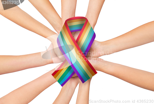 Image of female hands holding gay pride awareness ribbon