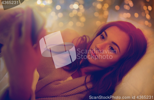 Image of young woman with smartphone in bed at home bedroom