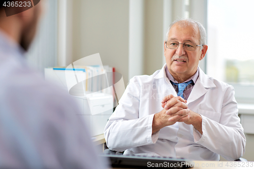 Image of senior doctor talking to male patient at hospital