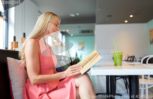 Image of woman with drink reading book at cafe