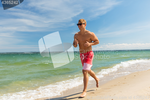 Image of happy man running along summer beach