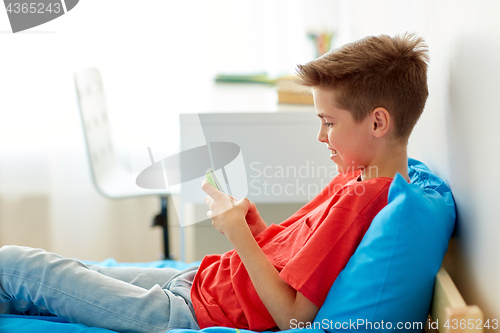 Image of happy smiling boy with smartphone at home