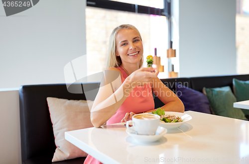 Image of happy young woman eating lunch at restaurant