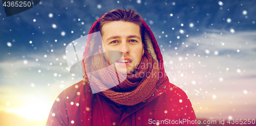 Image of happy man in winter jacket with hood outdoors