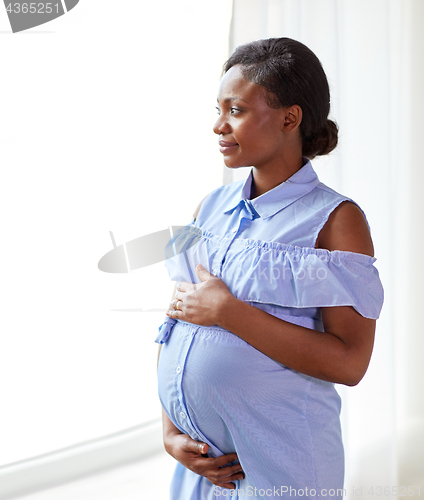 Image of pregnant woman looking through window at home