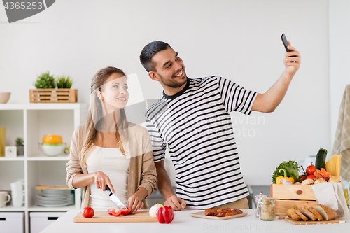 Image of couple cooking food and taking selfie at kitchen