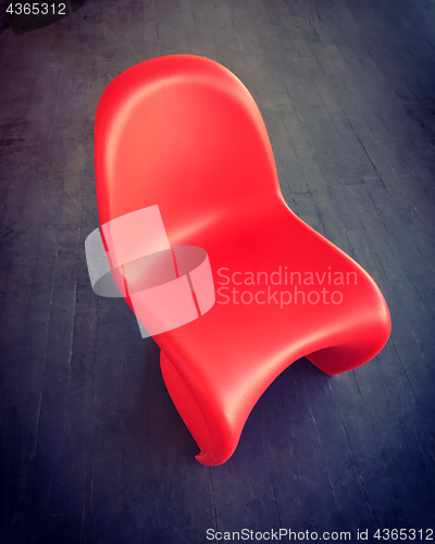 Image of Red plastic chair on dark wooden floor
