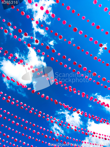 Image of Pink balls decoration against blue sky and clouds