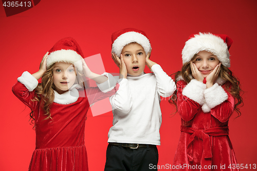 Image of The happy boy and girls in santa claus hats with gift boxes at studio