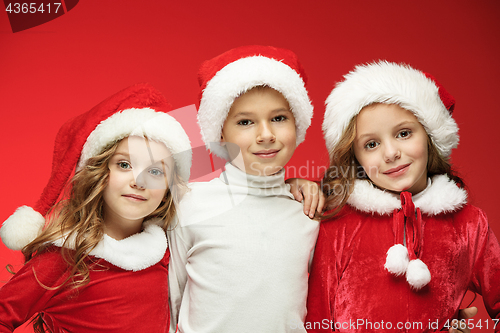 Image of The happy boy and girls in santa claus hats with gift boxes at studio