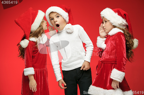 Image of The happy boy and girls in santa claus hats with gift boxes at studio