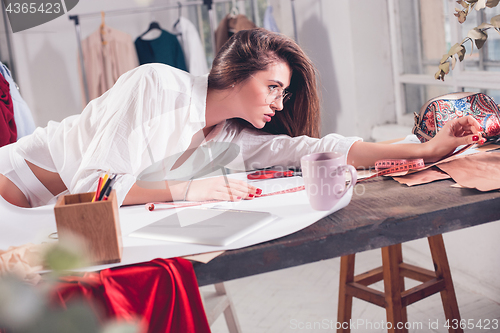 Image of Fashion designers working in studio sitting on the desk