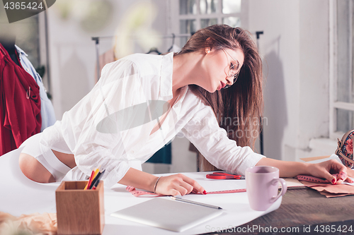 Image of Fashion designers working in studio sitting on the desk