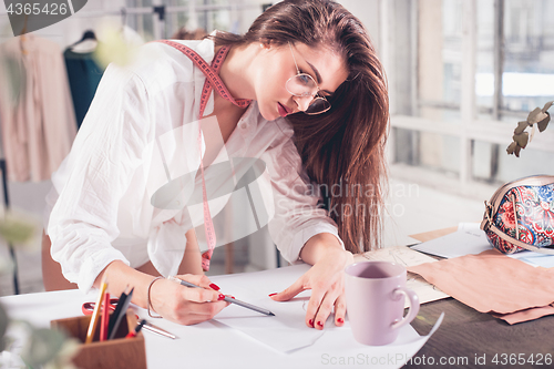 Image of Fashion designers working in studio sitting on the desk