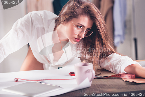 Image of Fashion designers working in studio sitting on the desk