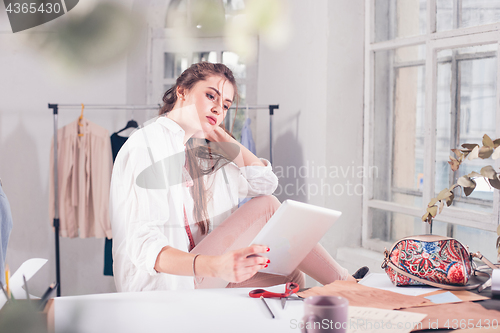 Image of Fashion designers working in studio sitting on the desk