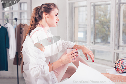 Image of Fashion designers working in studio sitting on the desk