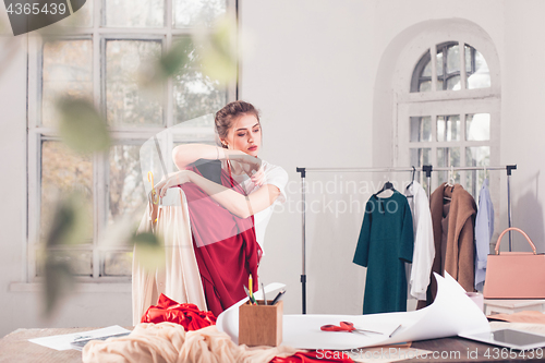 Image of Fashion designers working in studio sitting on the desk