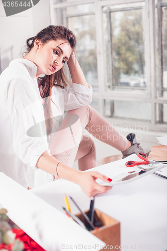 Image of Fashion designers working in studio sitting on the desk