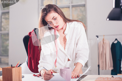 Image of Fashion designers working in studio sitting on the desk