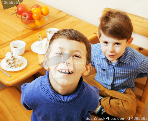 Image of little cute boys eating dessert on wooden kitchen. home interior