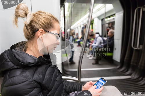 Image of Young girl reading from mobile phone screen in metro.