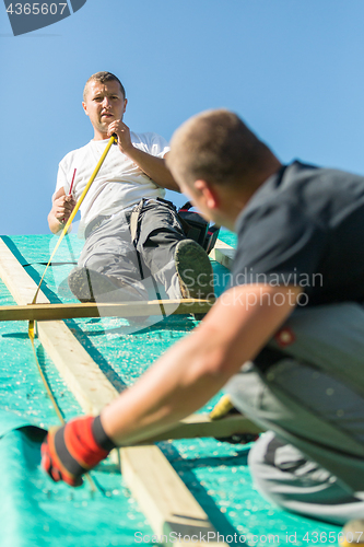 Image of Builders at work with wooden roof construction.