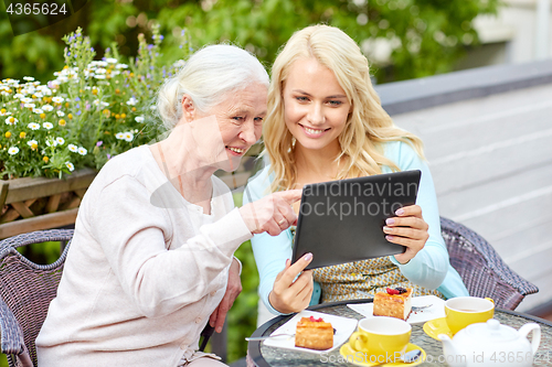 Image of daughter with tablet pc and senior mother at cafe
