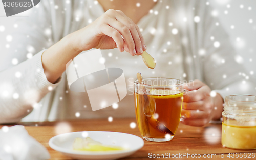 Image of close up of woman adding honey to tea with lemon