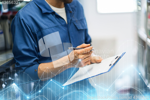 Image of auto mechanic with clipboard at car workshop