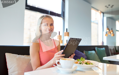 Image of happy young woman with tablet pc at restaurant