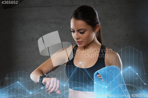 Image of young woman with heart-rate watch and towel in gym