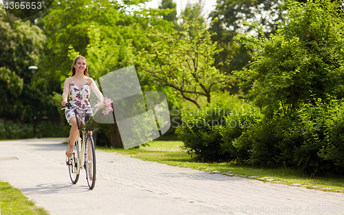 Image of happy woman riding fixie bicycle in summer park