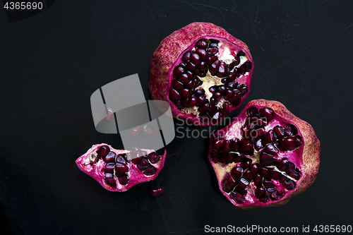 Image of Two pomegranates on a black scratched background. Top view