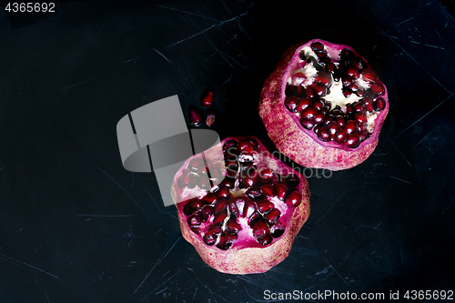 Image of Two pomegranates on a black scratched background. Top view