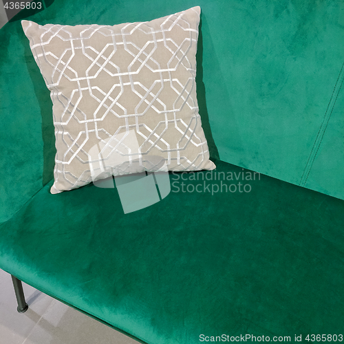 Image of Green velvet sofa with ornate cushion