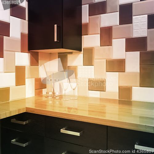 Image of Kitchen cabinets and tiled backsplash in warm colors