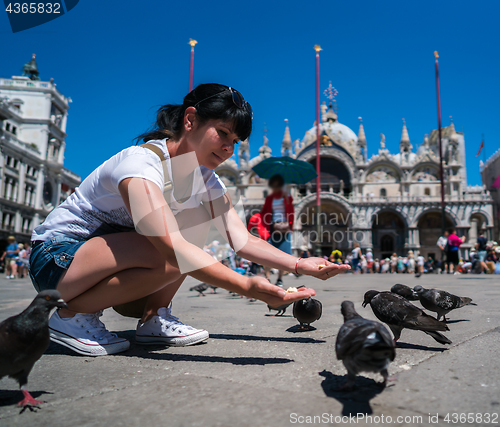 Image of Woman tourist feeding pigeons in the square - St. Marks Square -