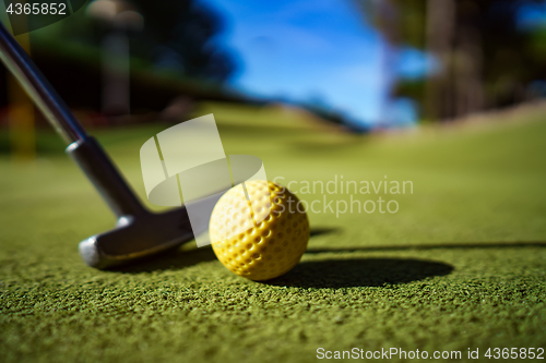 Image of Mini Golf yellow ball with a bat at sunset