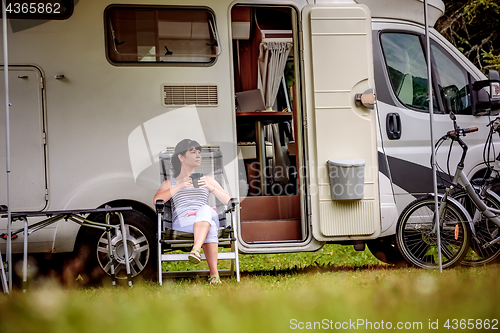 Image of Woman is standing with a mug of coffee near the camper RV.