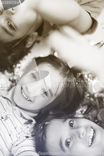 Image of kids  blowing confetti while lying on the floor