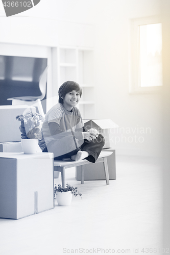 Image of boy sitting on the table with cardboard boxes around him