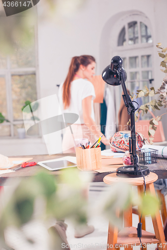 Image of Fashion designers working in studio sitting on the desk