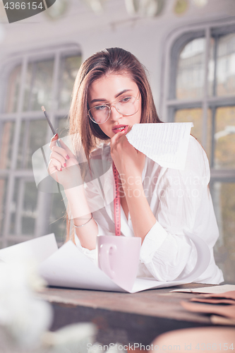 Image of Fashion designers working in studio sitting on the desk