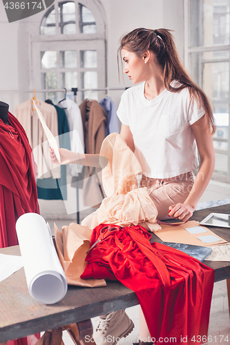 Image of Fashion designers working in studio sitting on the desk